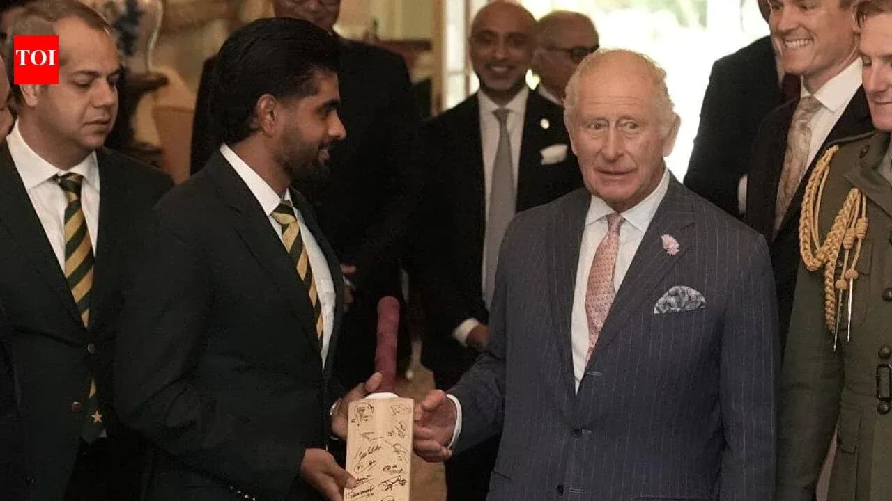 Cricket players presenting signed bat to King Charles