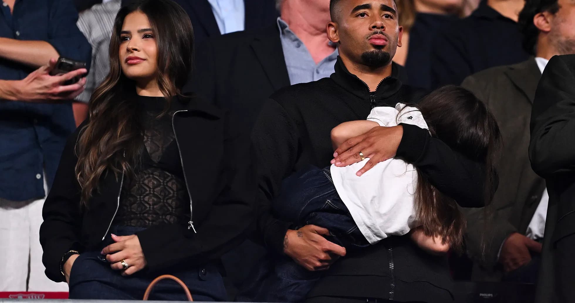 Couple watching event with child in arms Couple watching event with child in arms