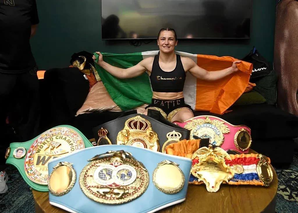 Female boxer holding Irish flag with championship belts Female boxer holding Irish flag with championship belts