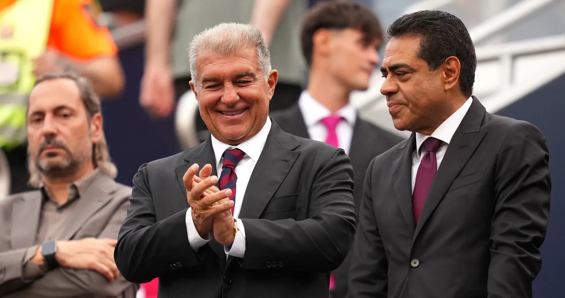 Two men in suits smiling and applauding at event Two men in suits smiling and applauding at event
