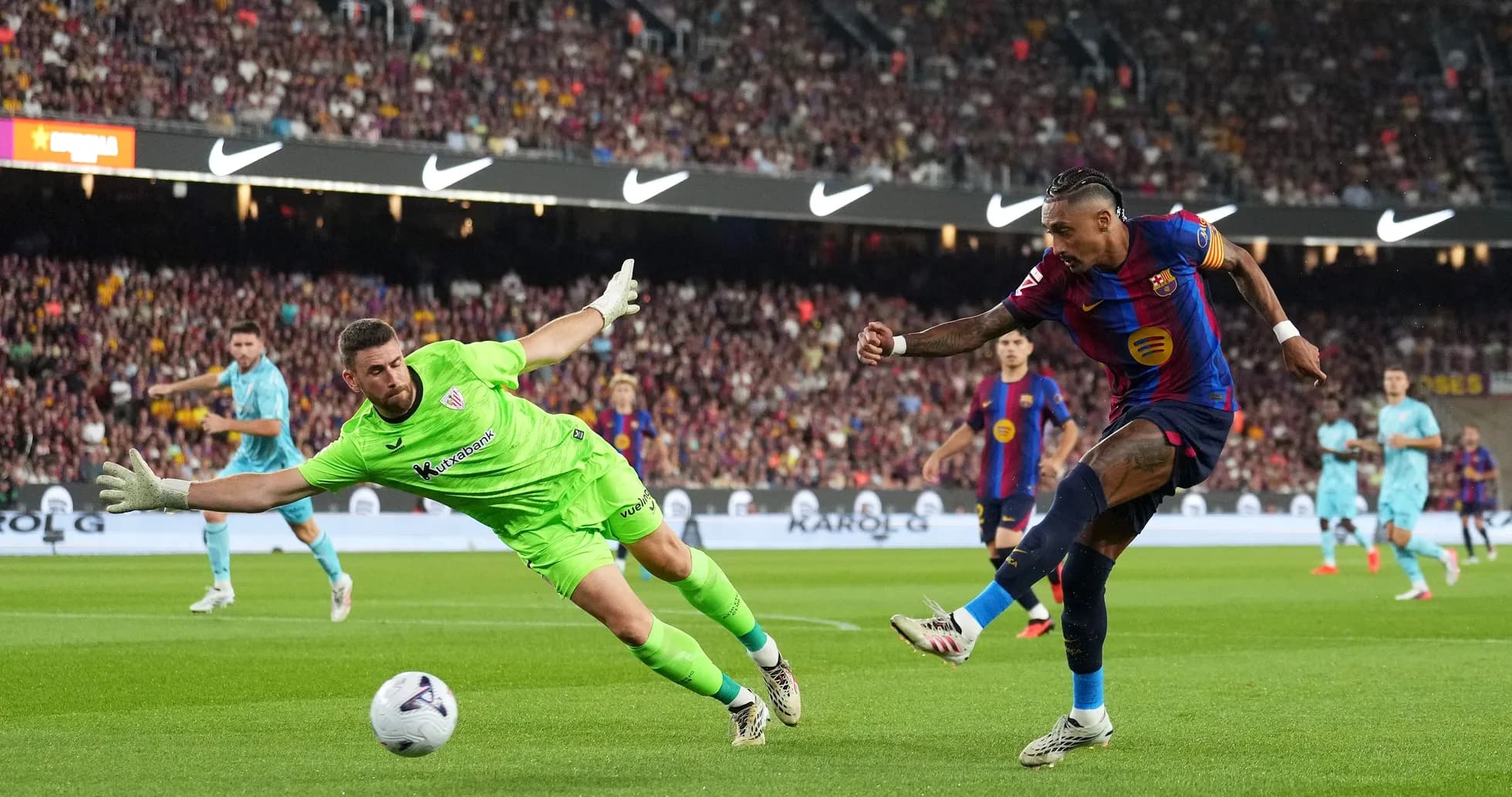 Player attempting to score while goalkeeper dives Player attempting to score while goalkeeper dives