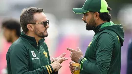 Two cricket coaches discussing strategy during practice Two cricket coaches discussing strategy during practice